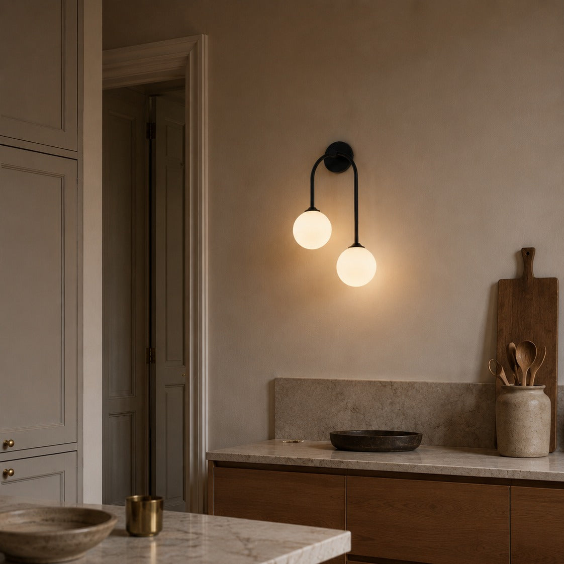 Black glass ball double wall light above a marble kitchen counter with ceramics
