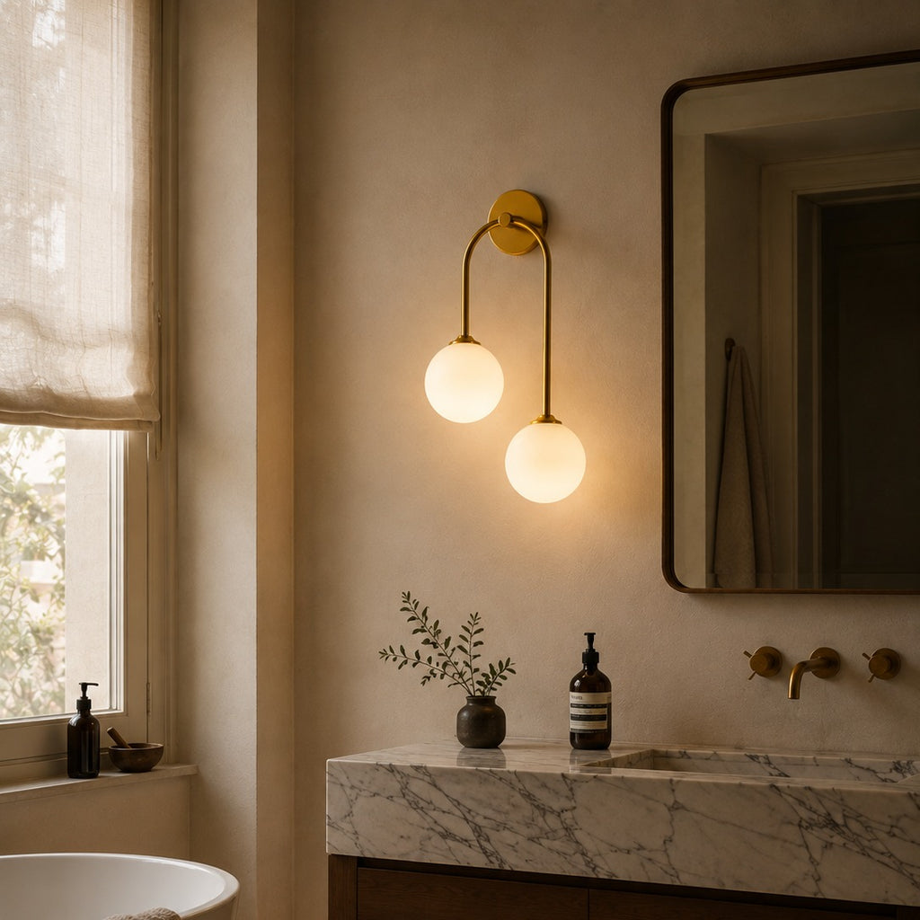 Gold glass ball double wall light beside a marble vanity mirror in a bathroom