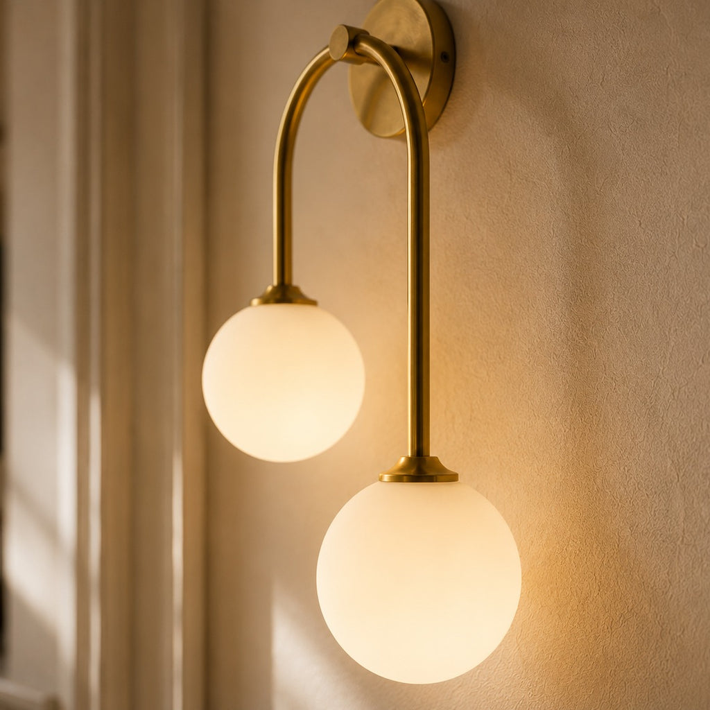 Gold glass ball double wall light beside a bathroom mirror with soft window light