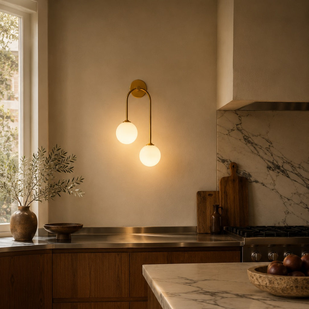 Gold glass ball double wall light above a veined marble kitchen worktop