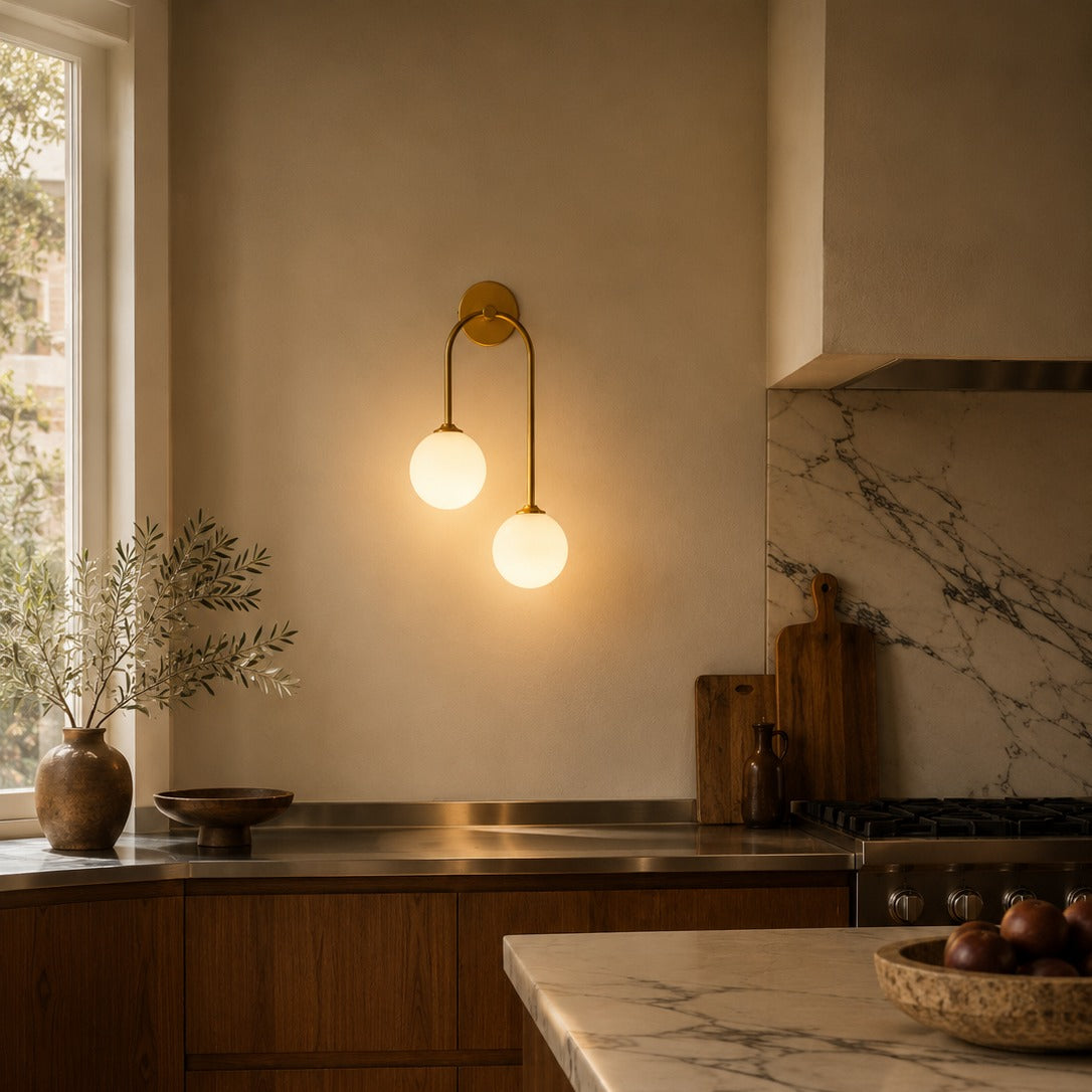 Gold glass ball double wall light above a veined marble kitchen worktop