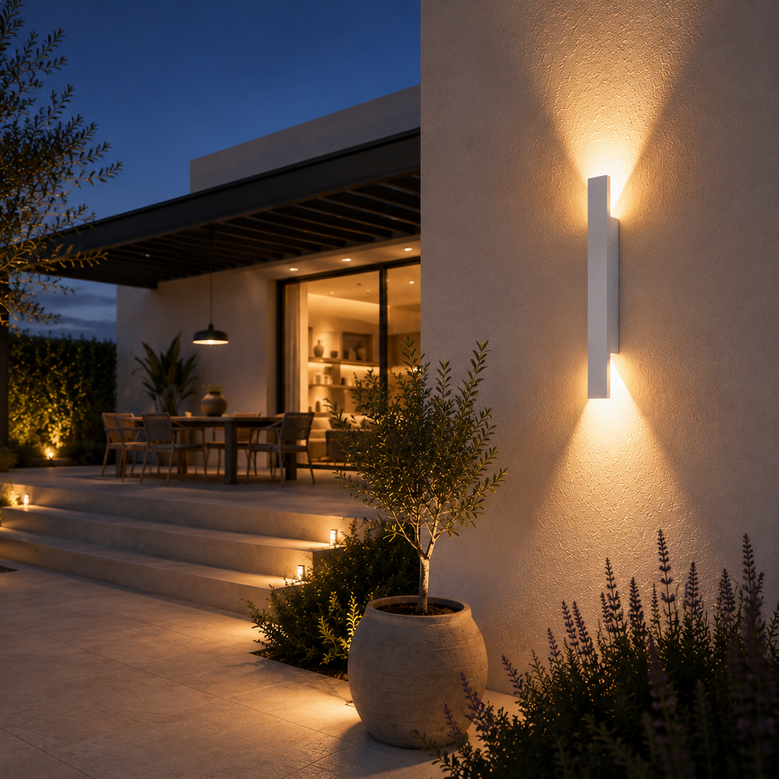 Aluminium up-down outdoor wall light beside a covered terrace at dusk