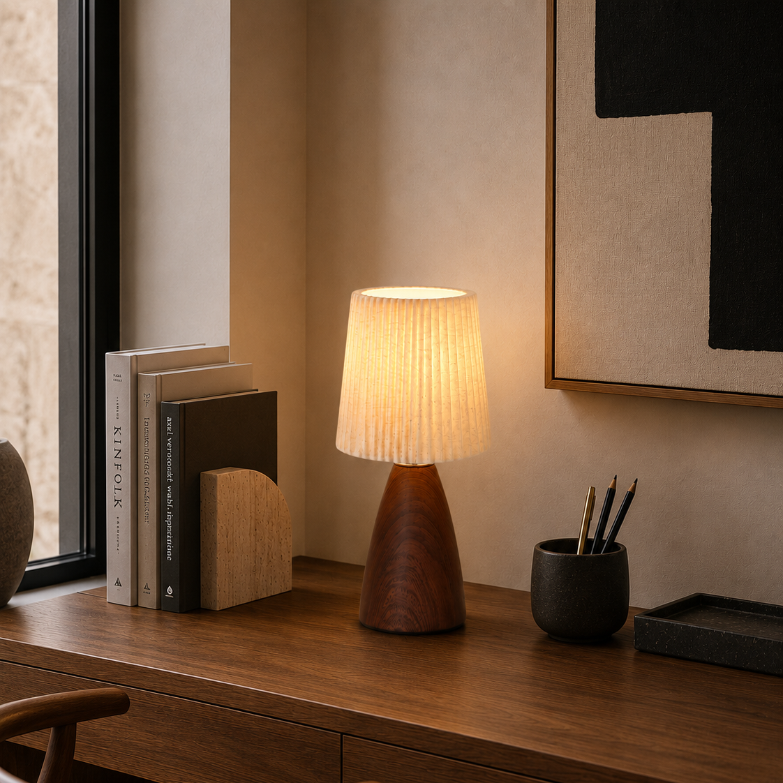 Pleated fabric table lamp on a desk beside a woven chair