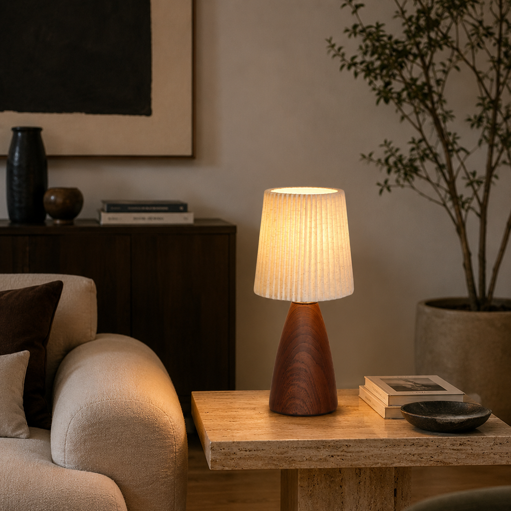 Pleated fabric table lamp on a side table beside a plant