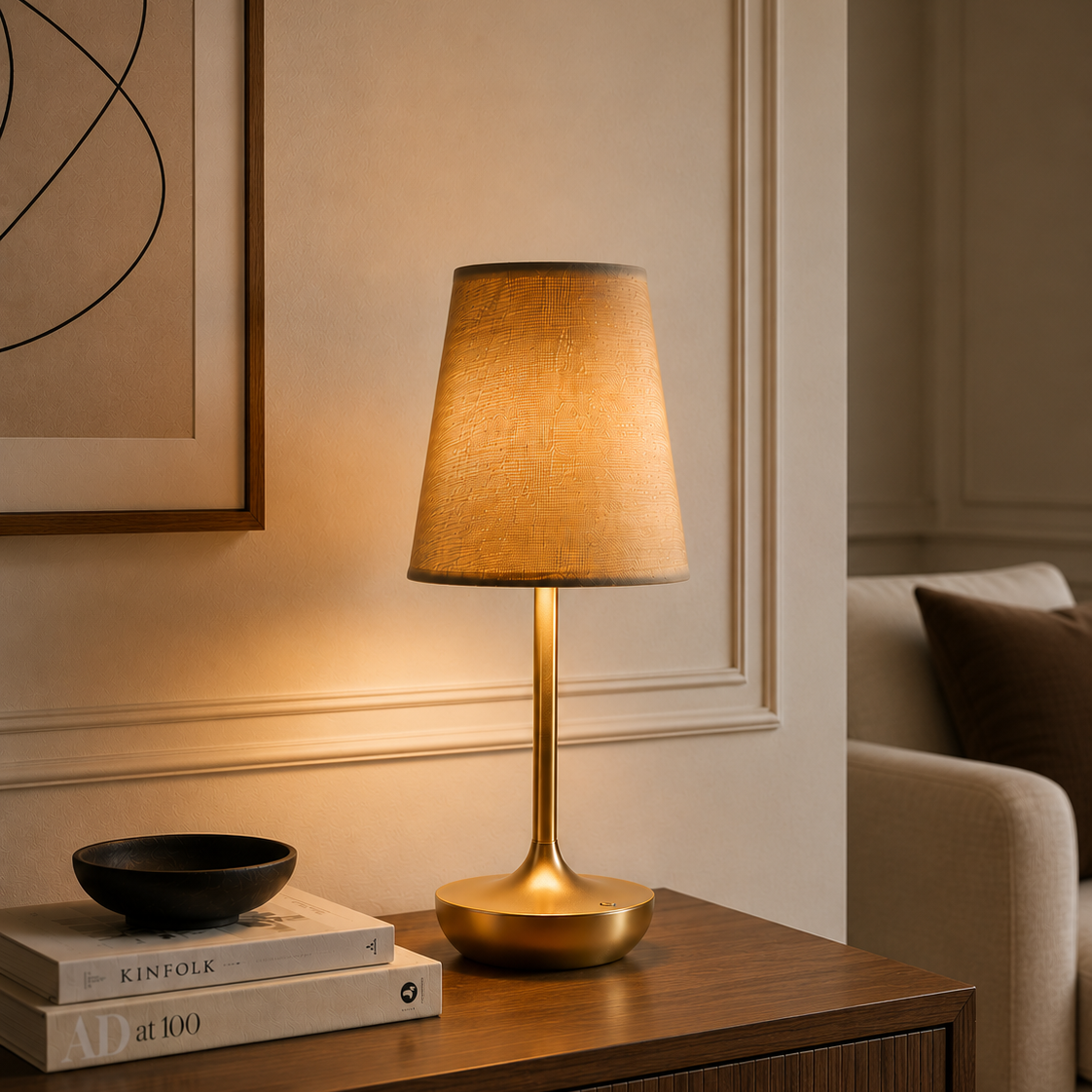 Rechargeable fabric-shade table lamp beside stacked books on a console